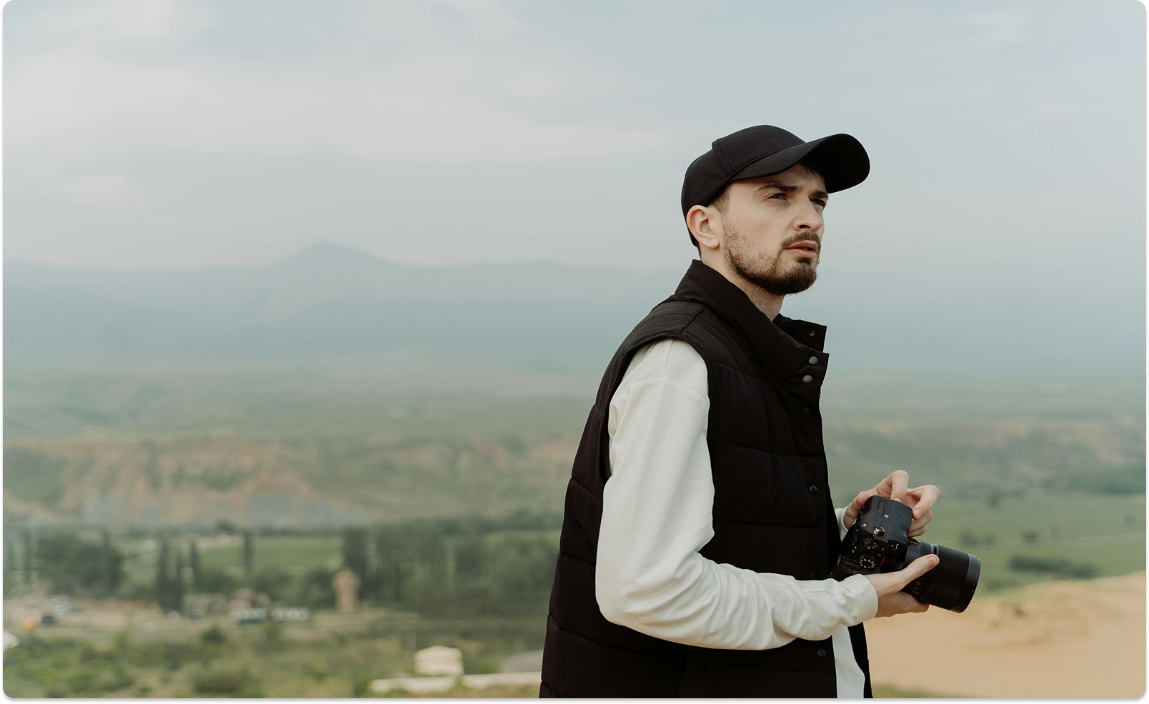 Julian Voss standing on a ridge overlooking a misty valley, camera in hand