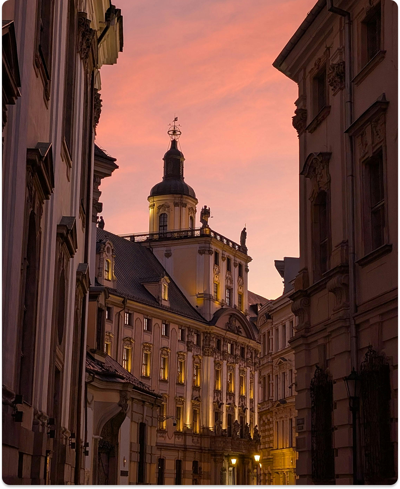A historic building glowing at sunset between two street facades